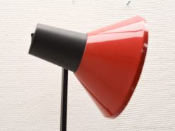 Modern red lamp with glossy conical shade and sleek black neck for contemporary interiors.