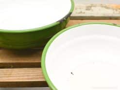 Charming vintage green enamel bowls with white interiors, ideal for rustic kitchen decor.