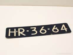 Vintage black and white registration plate HR-36-64, showcasing nostalgic wear and character.