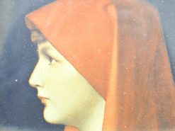 Elegant young woman in a red headscarf, gazing thoughtfully against a dark background.