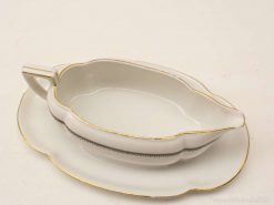 Elegant porcelain gravy boat with gold trim and matching underplate for stylish dining.