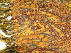 Elegant paisley scarf in mustard yellow and burgundy with playful fringes. Versatile fashion accessory.