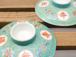 Turquoise porcelain saucers with intricate designs and Chinese symbols, perfect for decor and ceremonies.