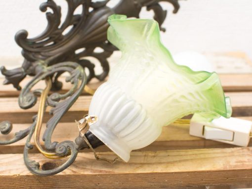 Charming vintage lamp with fluted green shade and elegant wrought iron bracket for cozy decor.