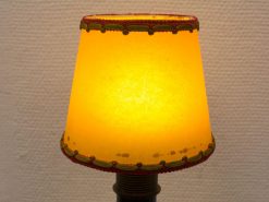 Vintage lamp with warm yellow shade and decorative green and burgundy trim for cozy ambiance.