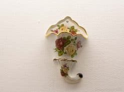 Elegant porcelain wall pocket with rose design and gold trim for stylish floral display.