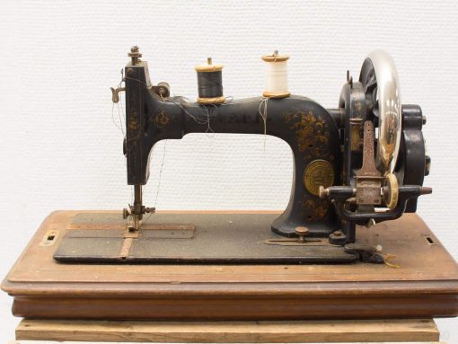 Antique sewing machine with elegant black and gold design, featuring colorful spools ready for use.