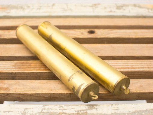 Antique brass cylinders on rustic wood, showcasing beauty and history in vintage decor.