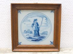 Charming ceramic plate depicting a shepherd with animals, framed in rustic wood.