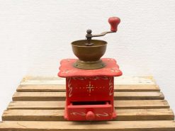 Vintage red coffee grinder with brass mechanism and decorative patterns, perfect for any kitchen.