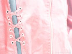 Trendy pink jacket with lace-up detail and gray panel, perfect for a stylish look.