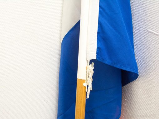 Elegant blue and white flag on a natural wooden pole, symbolizing pride and identity.