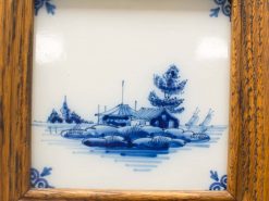 Serene Delft Blue landscape tile framed in rustic wood, showcasing a tranquil village scene.