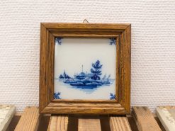 Charming blue and white tile landscape in rustic wooden frame, ideal for home decor.