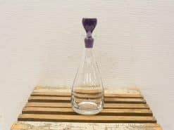 Elegant glass decanter with purple stopper, perfect for serving and showcasing beverages.