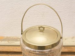 Vintage glass jar with golden lid and handle, perfect for decor and storage.