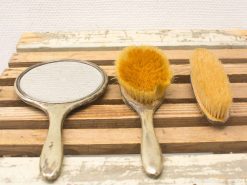 Vintage grooming tools set featuring a decorative mirror and elegant hairbrushes.