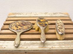 Vintage tortoiseshell grooming set: mirror, hairbrush, and small brush for elegant vanity decor.