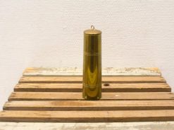 Polished brass cylinder on rustic wood, embodying vintage charm and craftsmanship.