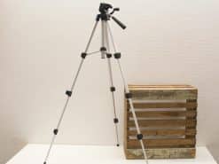 Sleek aluminum tripod with rustic wooden crate for photography and videography setups.