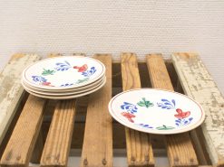 Colorful hand-painted ceramic plates stacked on a rustic wooden surface for charming decor.