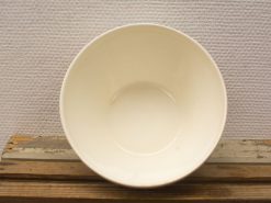 Elegant white bowl on rustic wooden table, perfect for serving or decoration.