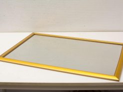 Elegant rectangular mirror with polished gold frame, adding charm and sophistication to any space.