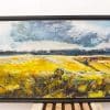 Vibrant golden fields beneath dramatic clouds in a captivating rural landscape painting.