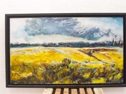 Vibrant golden fields beneath dramatic clouds in a captivating rural landscape painting.