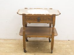 Elegant vintage wooden side table with floral inlay, drawer, and turned legs on wheels.