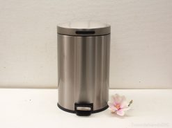 Sleek stainless steel trash can with foot pedal, lid, and flower accent for modern decor.