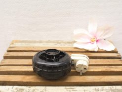 Black wheel and delicate flower highlight the harmony of nature and technology on rustic wood.