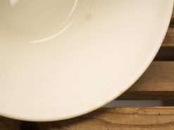 Elegant cream porcelain bowl on rustic wooden table, ideal for cozy dining experiences.