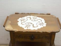 Charming vintage wooden table with lace design and decorative handles, perfect for cozy interiors.