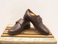 Stylish brown leather shoes with buckle detail on a rustic wooden crate.