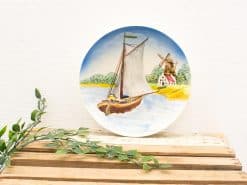 Serene ceramic plate featuring a sailing boat amidst a tranquil landscape and windmill.