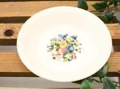 Elegant vintage ceramic plate with pastel floral design on a rustic wooden background.