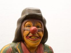 Vibrant wooden clown sculpture exuding joy with colorful costume and expressive features.