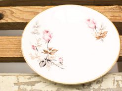 Elegant porcelain plate with pink rose design, gold trim, perfect for decor or serving.