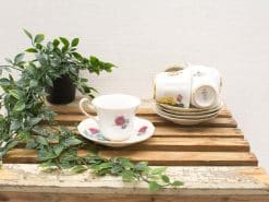 Elegant vintage teacup and saucer with floral motifs and greenery for a cozy tea time.