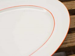 Elegant white serving plate with red trim, perfect for exquisite dining presentations.