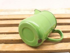 Vintage green enamel pitcher on rustic wood, blending charm and functionality in any space.