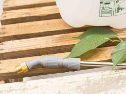 Ergonomic garden sprayer nozzle on rustic wood, perfect for watering vibrant plants.