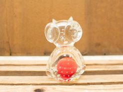 Playful glass owl figurine with a red polka-dotted ball, perfect for decor.