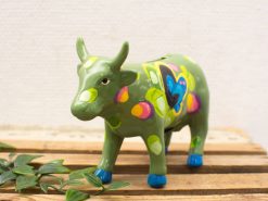 Whimsical hand-painted green cow bank with colorful spots and butterfly design for playful decor.