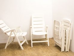 Versatile white plastic outdoor chairs for lounging and dining in a minimalist setting.