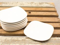 Elegant white square plates on rustic wooden table, perfect for modern dining experiences.