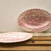 Elegant pink and white vintage ceramic platters with intricate pastoral designs for display or use.