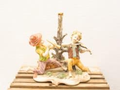 Charming vintage figurine of two children joyfully making music with a flute and violin.