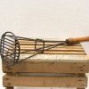 Vintage potato masher with wooden handle and durable metal head for mashing vegetables.